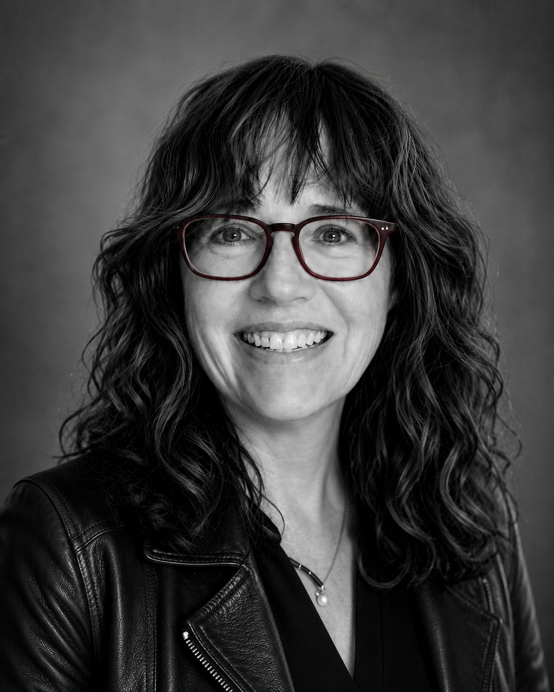 Portrait of Eileen M. Otis wearing red glasses and a black leather jacket